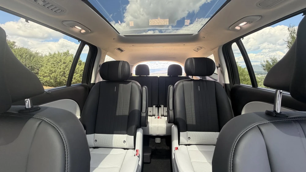 Petit SUV urbain blanc Hyundai Casper Electric, stationné sur une surface en terre battue près d'un plan d'eau arboré