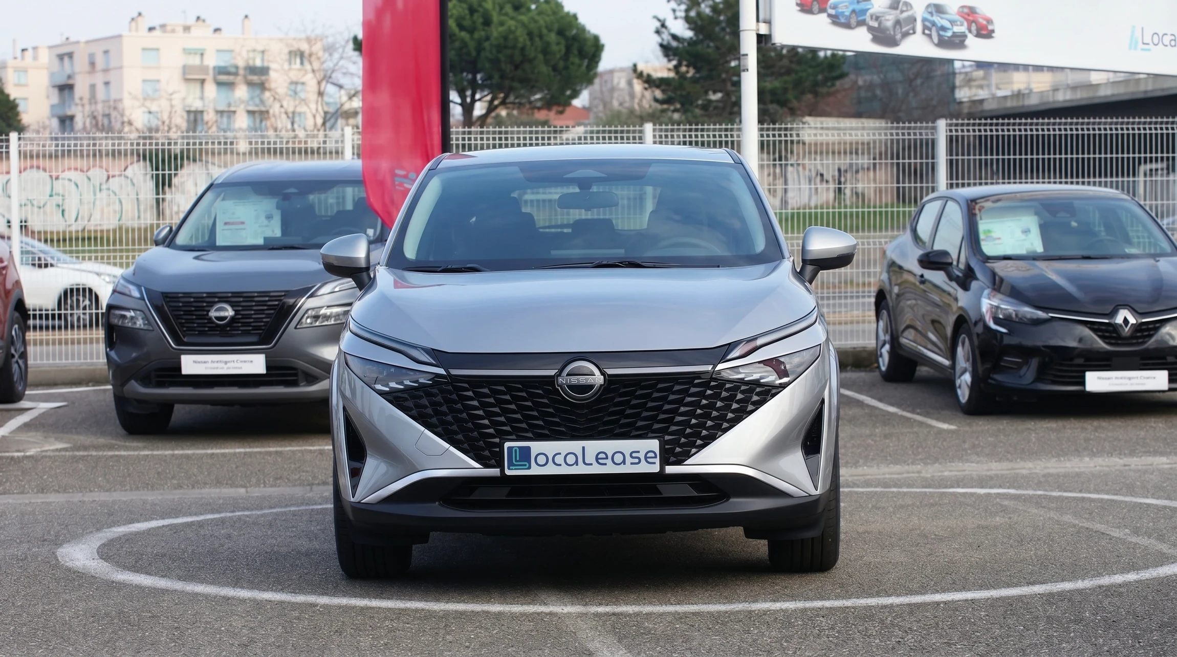 Photographie professionnelle en plongée d'un parking extérieur bien organisé, montrant plusieurs véhicules de couleurs variées alignés en rangées régulières. La scène met l'accent sur la clarté, l'ordre et l'efficacité organisationnelle. Au premier plan, en arrière-plan flou, on peut voir un gestionnaire de parc en tenue professionnelle consultant une tablette ou document, illustrant le suivi et l'administration de la flotte. L'image doit transmettre une impression de maîtrise, de professionnalisme et de gestion organisée.